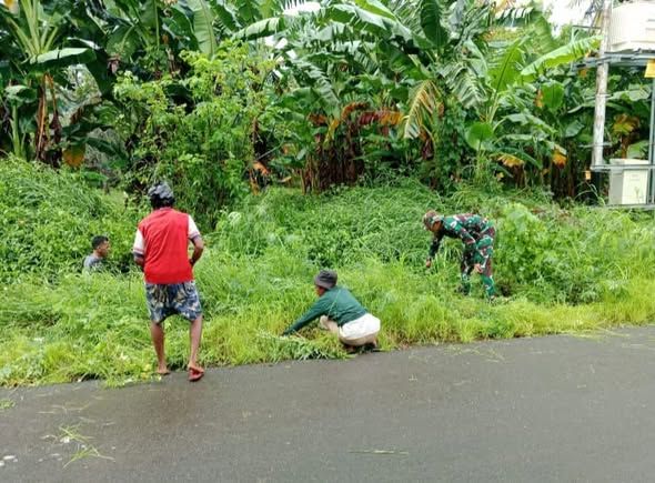 Babinsa Nagawutung Bersama Warga Bersihkan Bahu Jalan Desa Imulolong